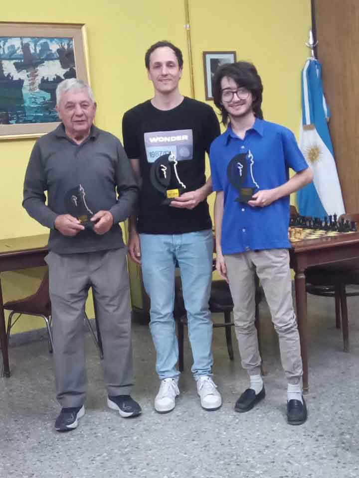 Lugones en el centro, flanqueado por Rossi (izq.) y Llanos (der.) los otros ocupantes del podio.